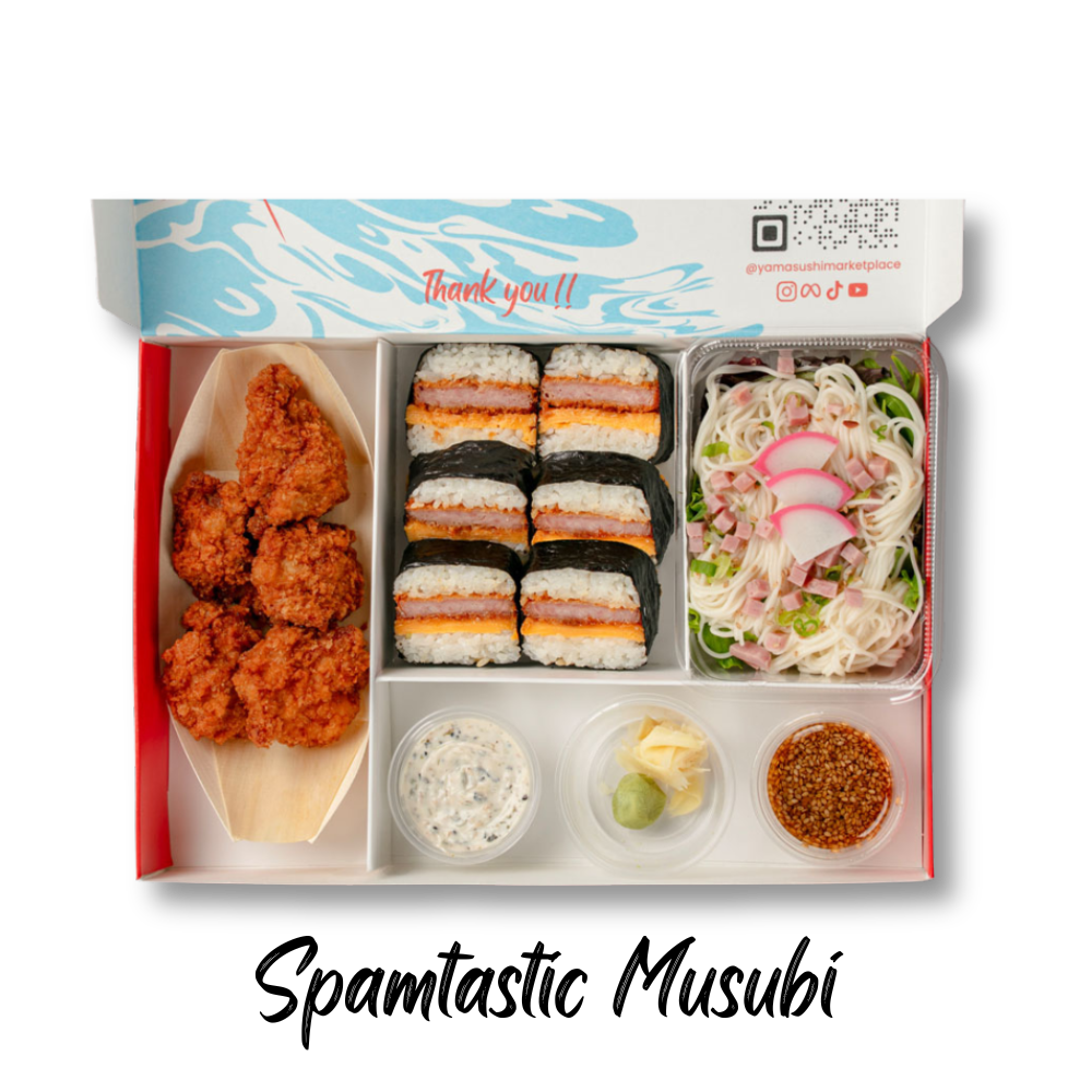 A bento box featuring fried chicken, sushi rolls, cold noodles with vegetables, and various dipping sauces.