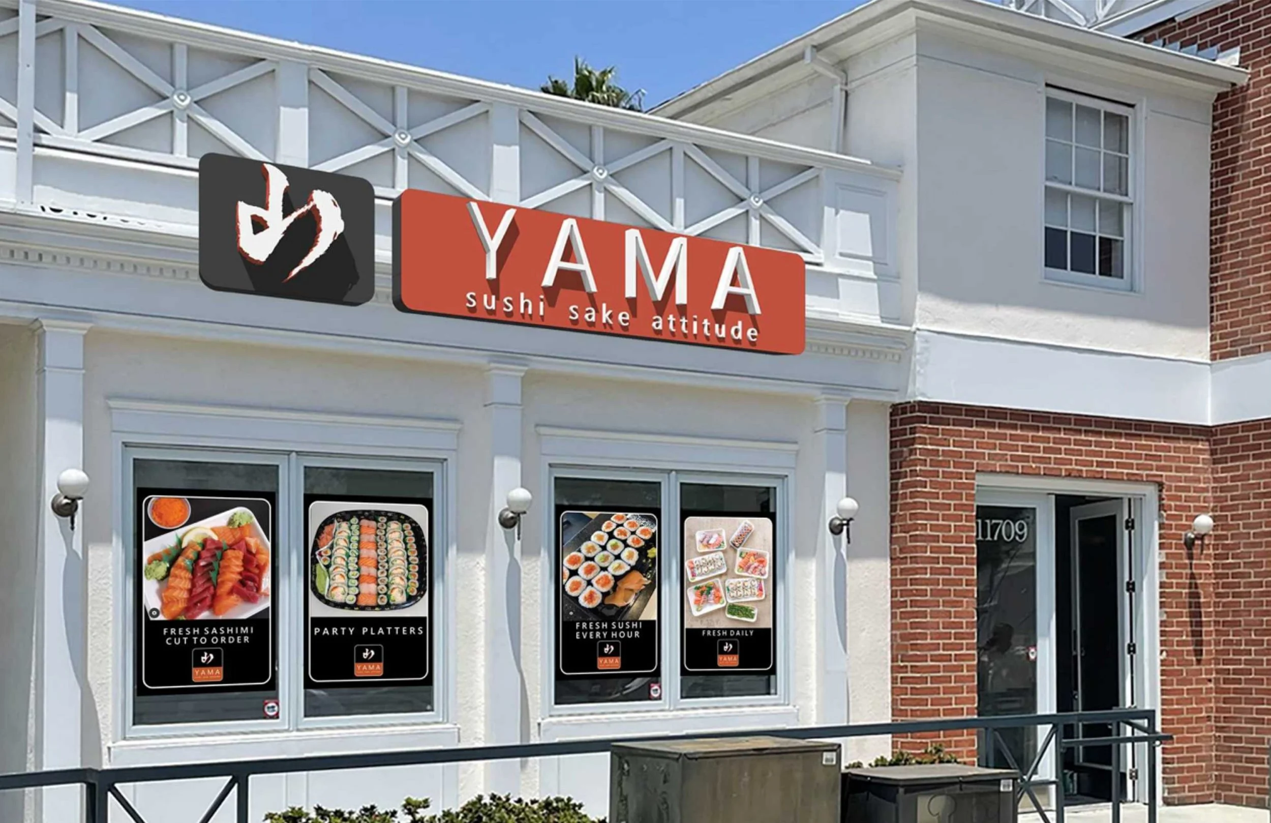Exterior of a restaurant named YAMA offering sushi, with posters advertising sashimi, sushi platters, and daily specials.